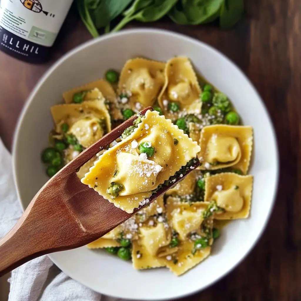 Kite Hill tortellini with green peas and dairy-free parmesan on a wooden fork, served in a white bowl.
